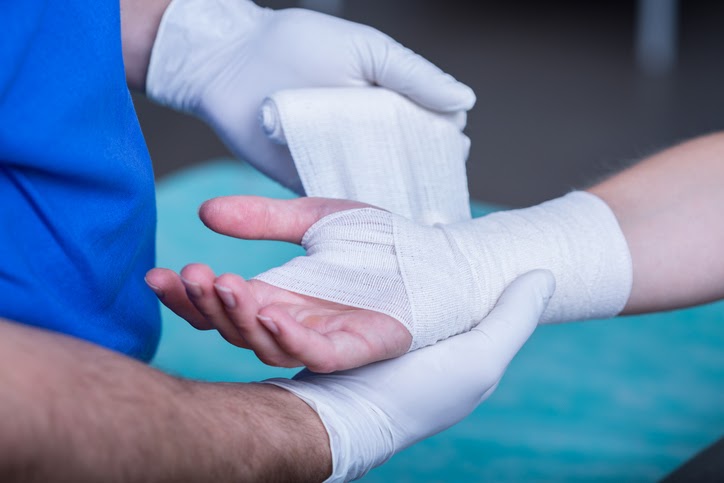 Close-up of male doctor bandaging a hand