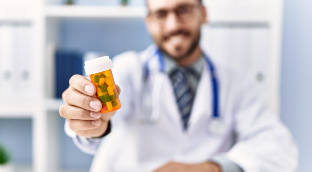 Medical professional holding medication bottle up to viewer