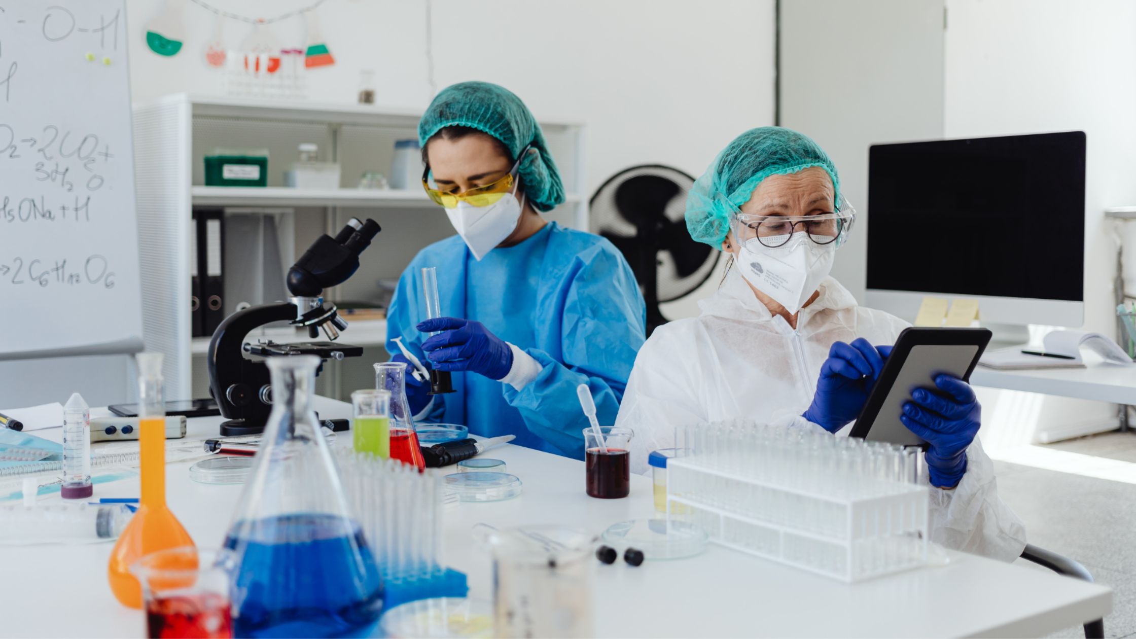Laboratory professionals wearing personal protective equipment while conducting scientific testing and handling medical samples.