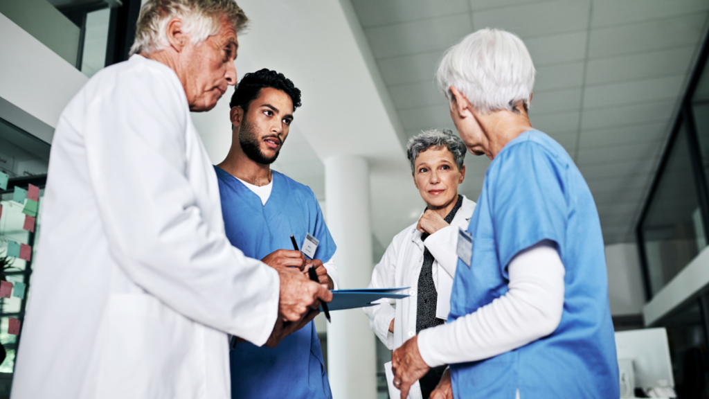 Healthcare professionals in scrubs and lab coats discussing patient care in a medical facility.